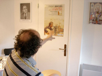 Taoufik désignant deux affiches accrochées au mur dans sa maison, à Savigny-sur-Orge : une affiche réprésentant “Cheikh Raymond” et une affiche d’un concert d’Enrico Macias à l’Olympia à Paris auquel il a participé. Juin 2005 © Atelier du Bruit