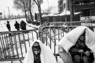 Des réfugiés patientent depuis plusieurs jours sous la neige, dans l’attente d’obtenir une place dans le centre humanitaire de la porte de La Chapelle. Paris, France. Février 2018. Photographie Michael Bunel