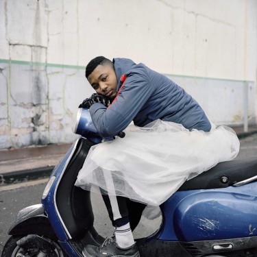 Photographie d'un jeune homme marseillais assis sur un scooter en tutu 
